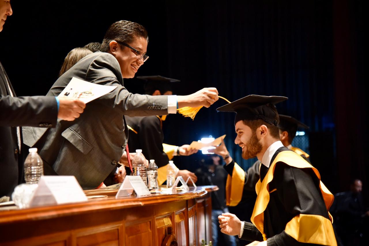 Rector del CUCS cambiando la mota del birrete a alumno graduado