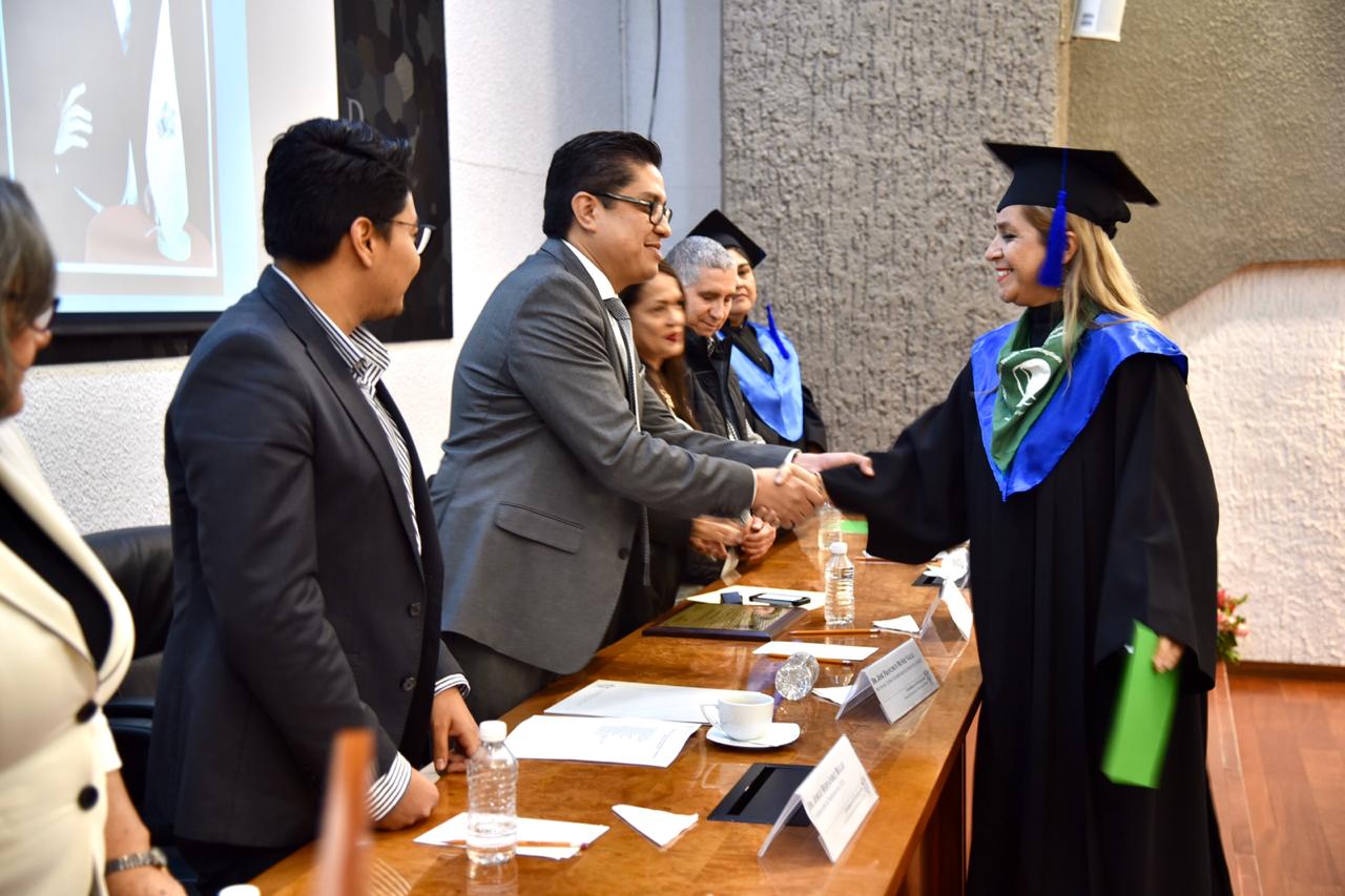 Rector entregando constancia a graduada saludándola de mano