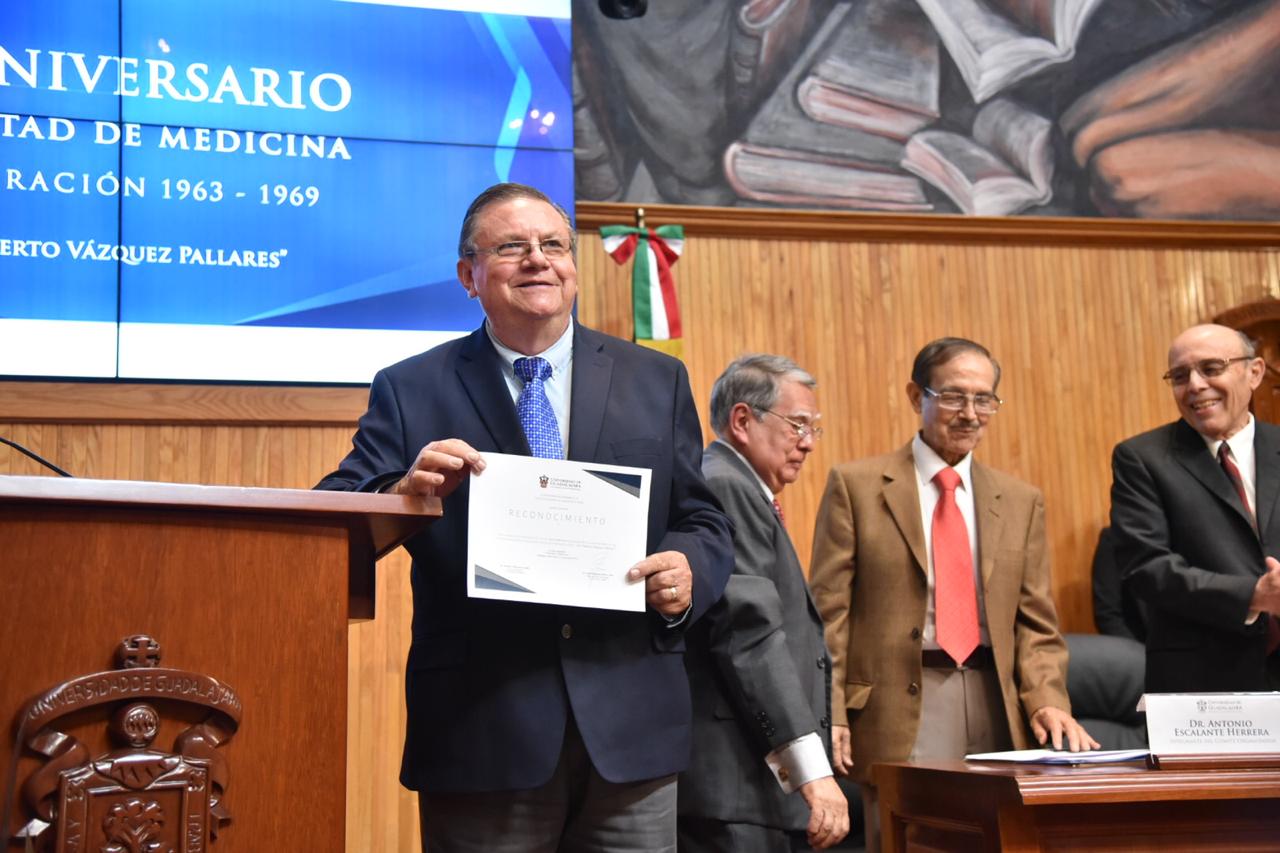 Graduado posando para la foto mostrando su constancia