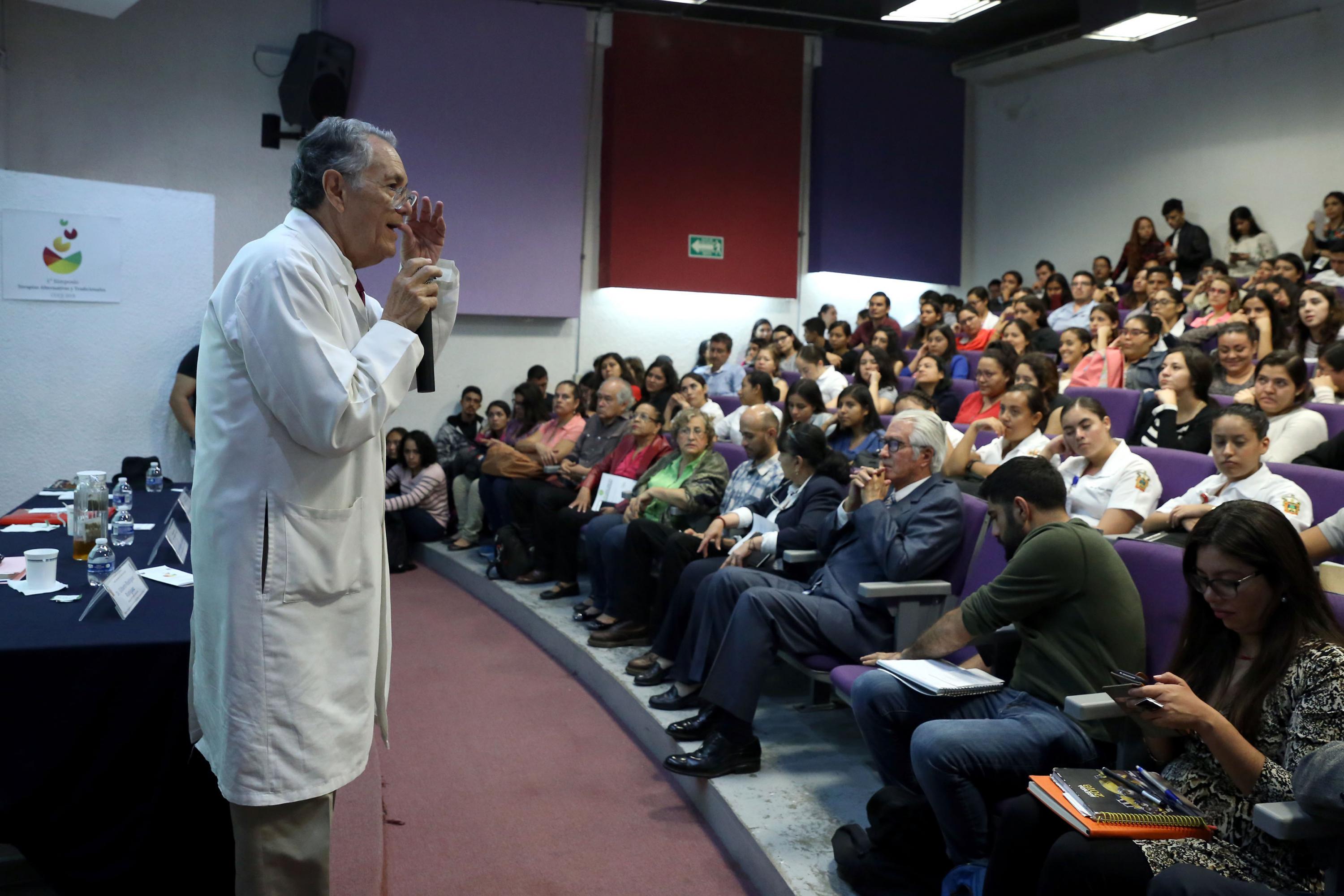 Dr. Javier García de Alba impartiendo conferencia y auditorio que luce lleno