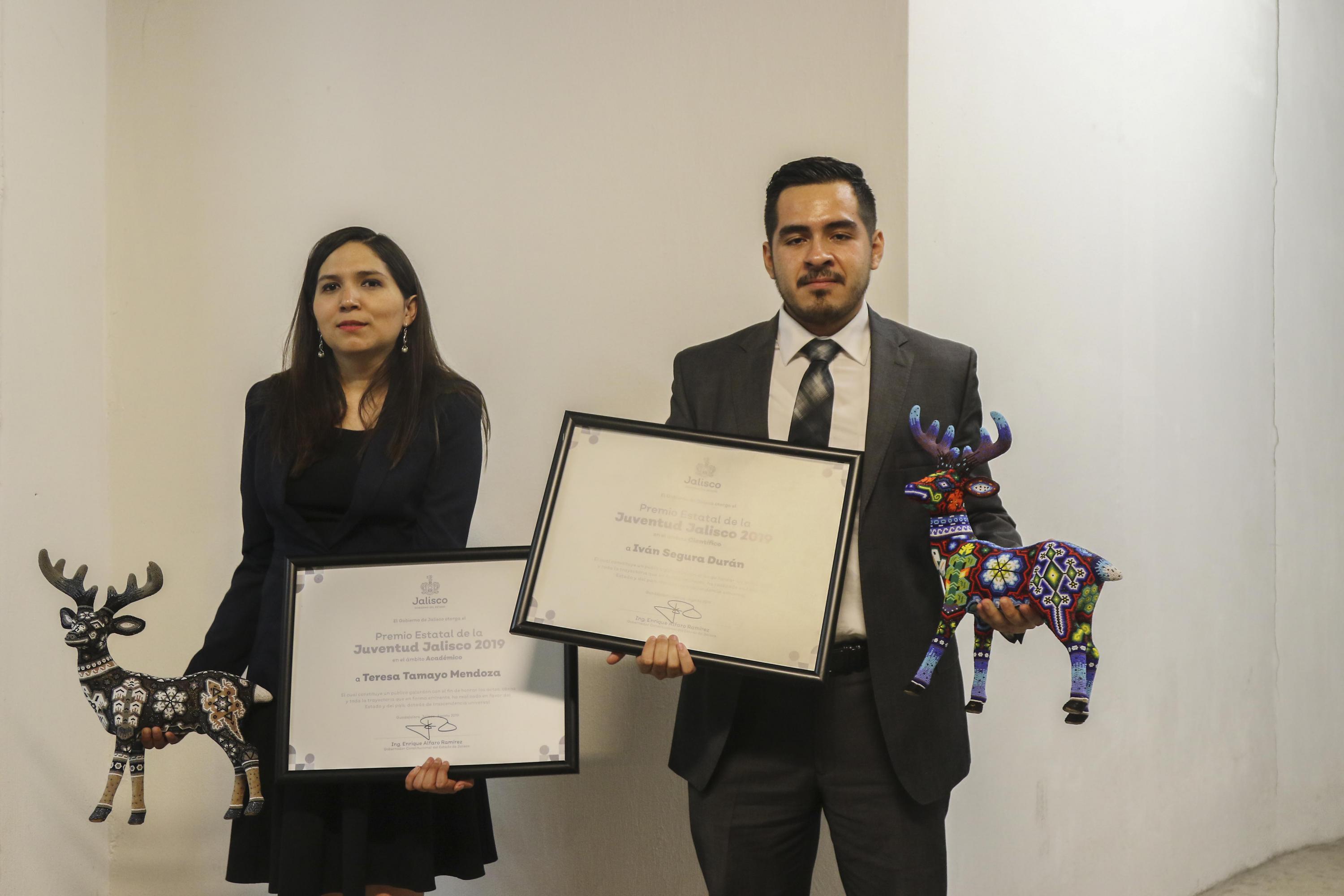 Egresados de UdeG exhibiendo su reconocimiento