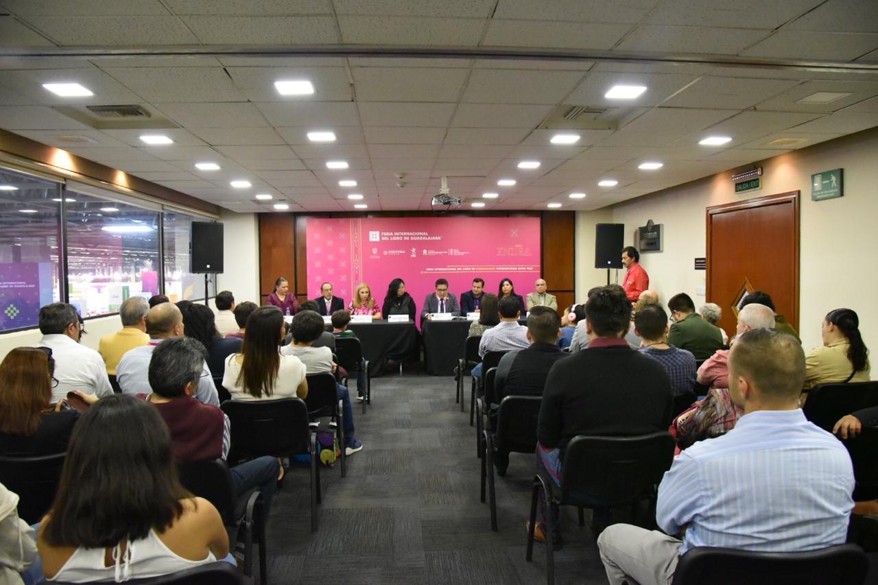 Miembros del presídium y toma general del evento desde atrás de la sala