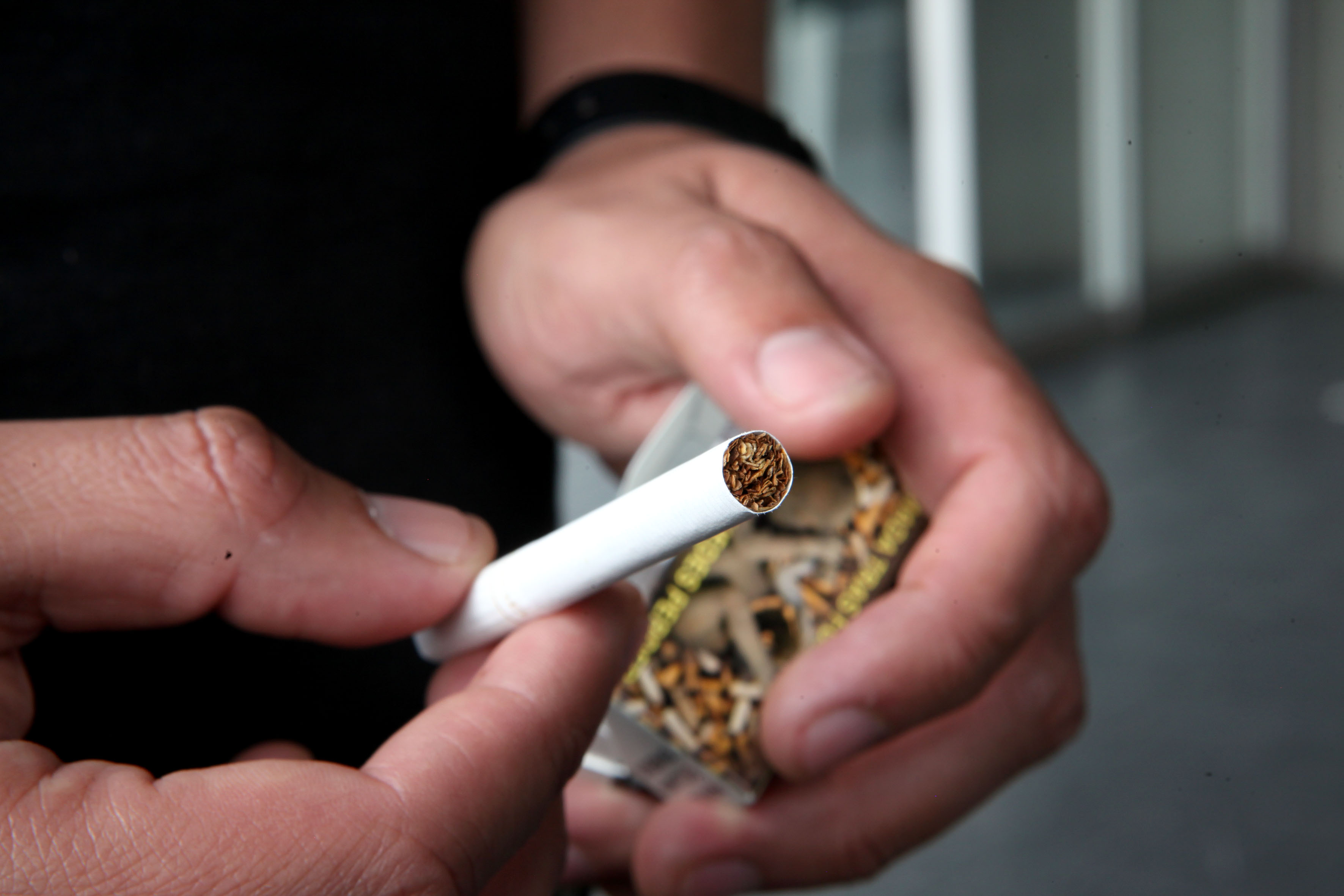 Un cigarro en las manos de un joven