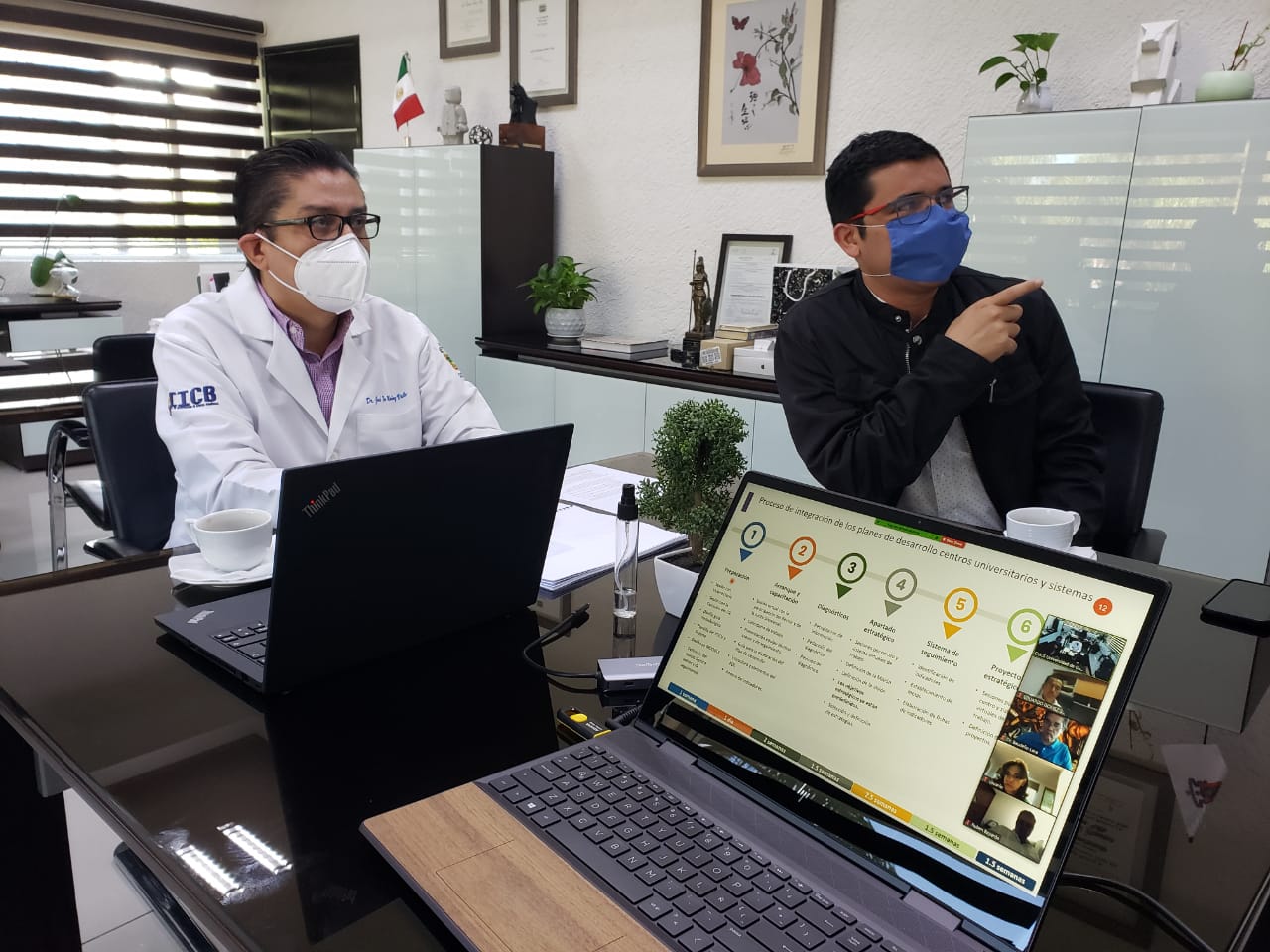 Rector analizando información en la pantalla de su oficina junto con el coordinador de Planeación