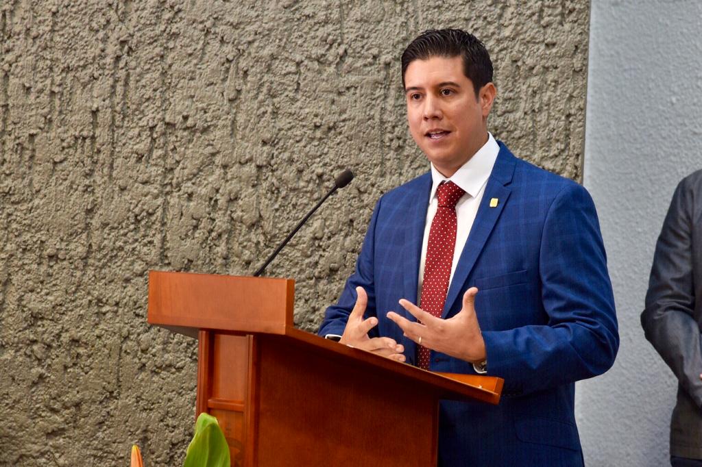 Padrino de Generación en pódium dirigiendo mensaje a graduados