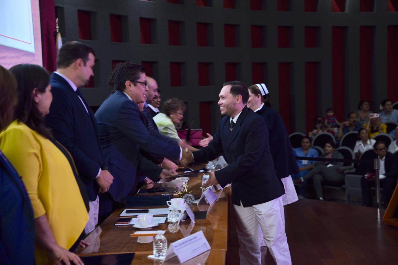 Graduado recibiendo de manos del rector su acta de terminación