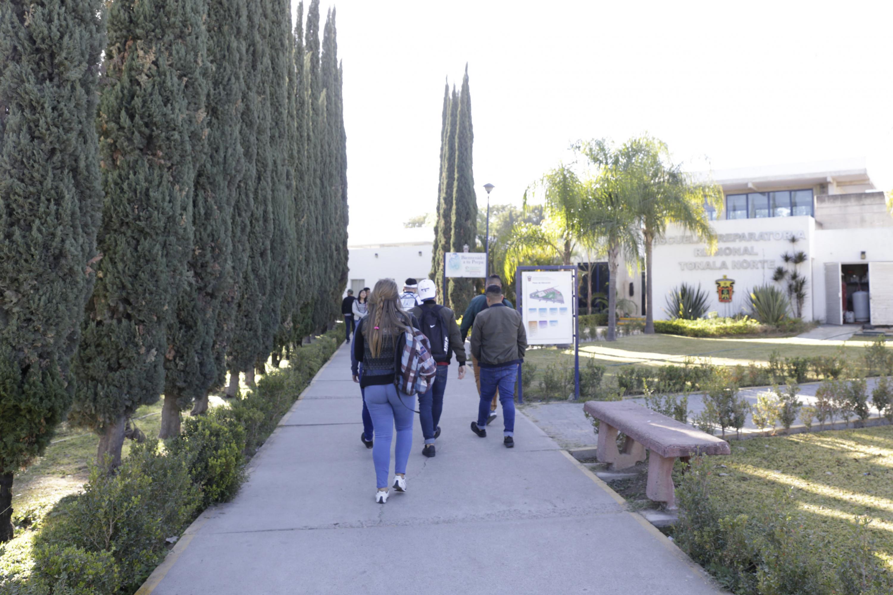 Alumnos caminando por pasillo de centro universitario
