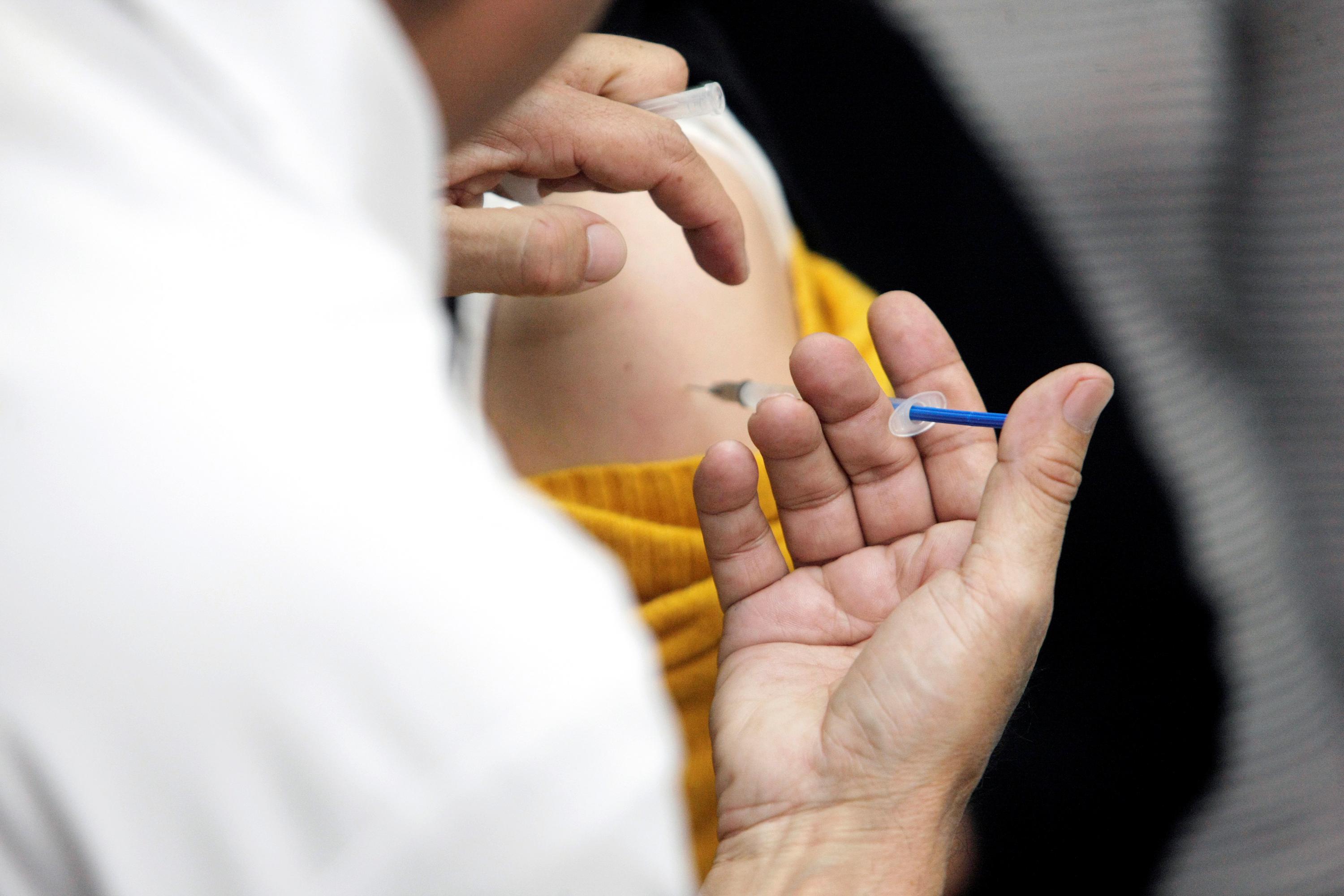 Mano de un médico aplicando una vacuna en el brazo