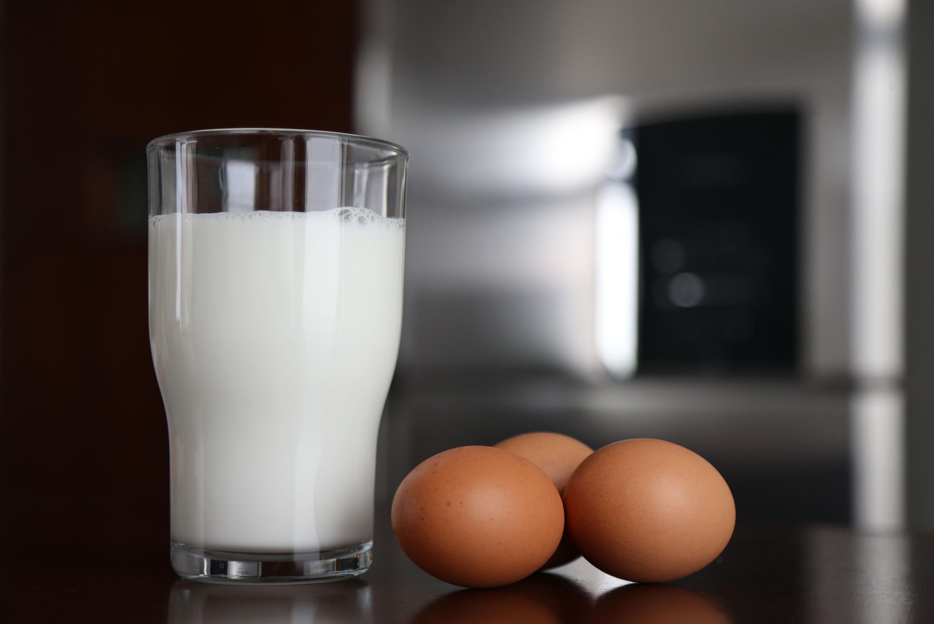 Fotografía de un vaso con leche y tres huevos en su cascarón