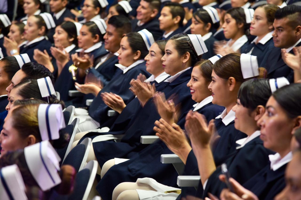 Enfermeras y enfermeros graduados en sus butacas aplaudiendo 