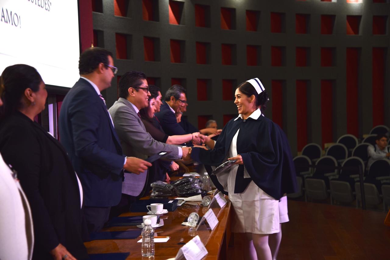 Enfermera graduada recibiendo acta de manos del rector del CUCS