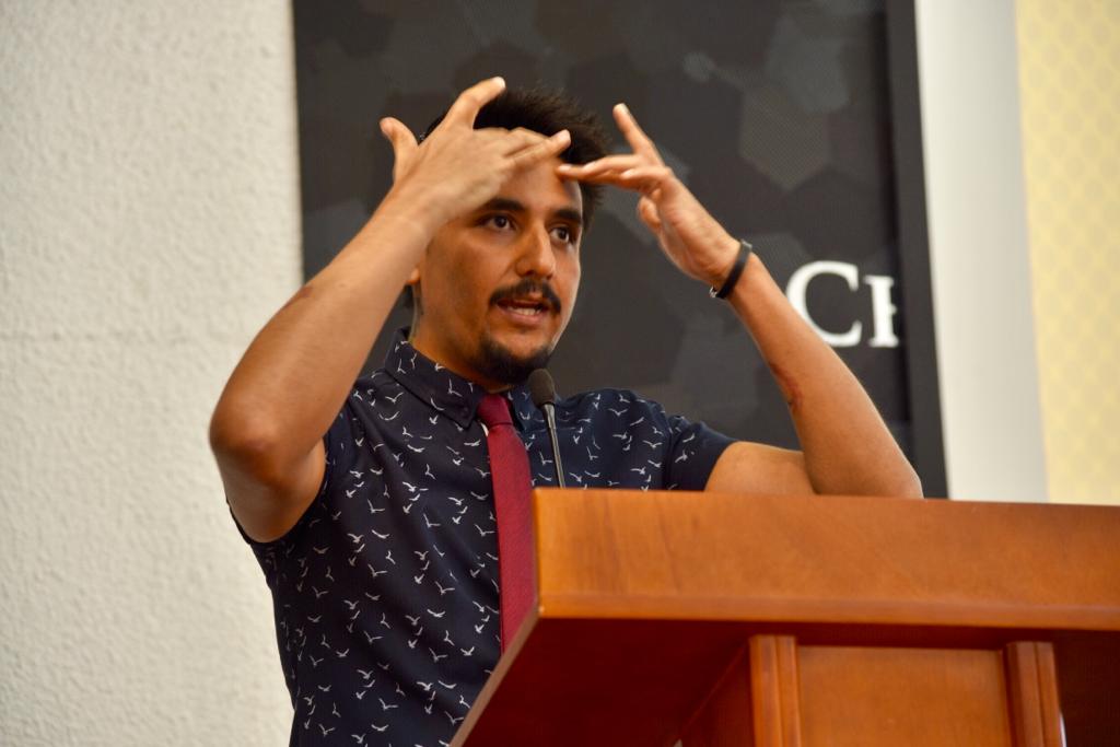 Ponente tocándose la cabeza con los dedos de las manos en el pódium