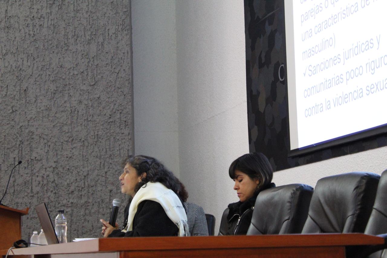 Especialista impartiendo conferencia, a su lado en la mesa del presídium la responsable de la Defensoría de Derechos Universitarios del CUCS