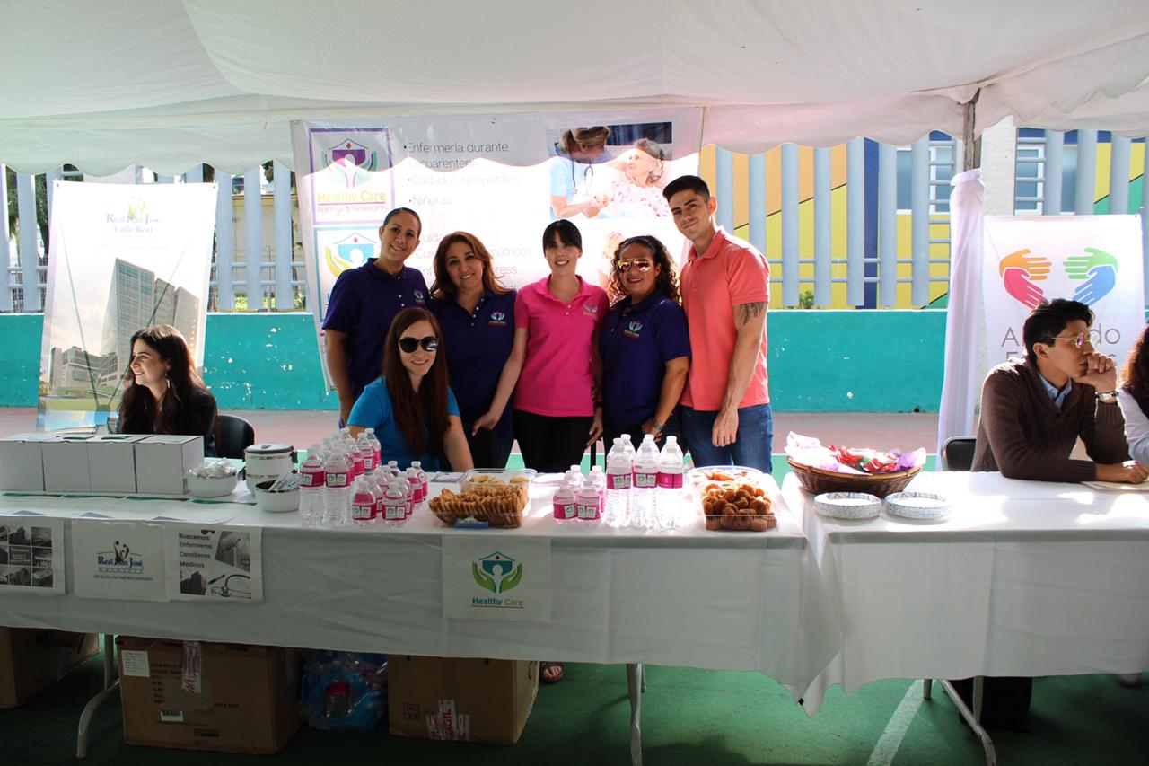 Empleadores posan para la foto tras un stand