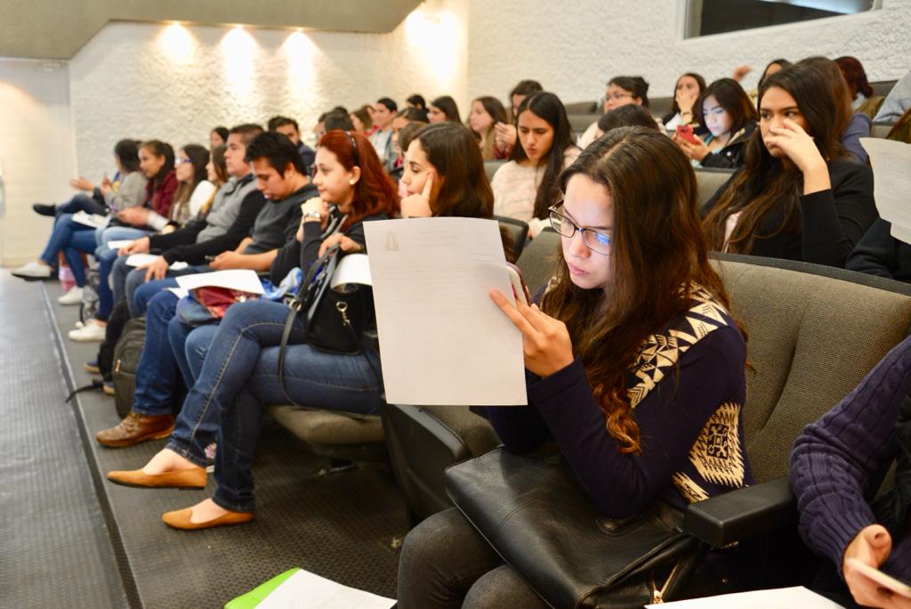 Alumna del CUCS revisando documentos en un auditorio