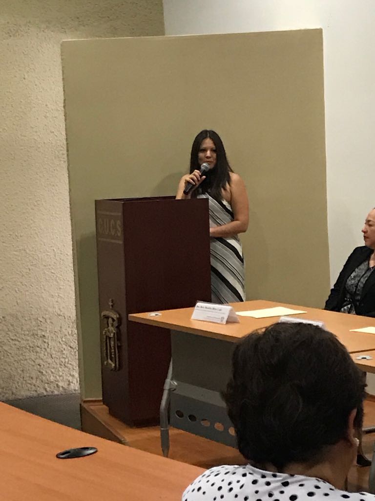 Mtra. Fabiola Macías Espinoza al micrófono en el podio