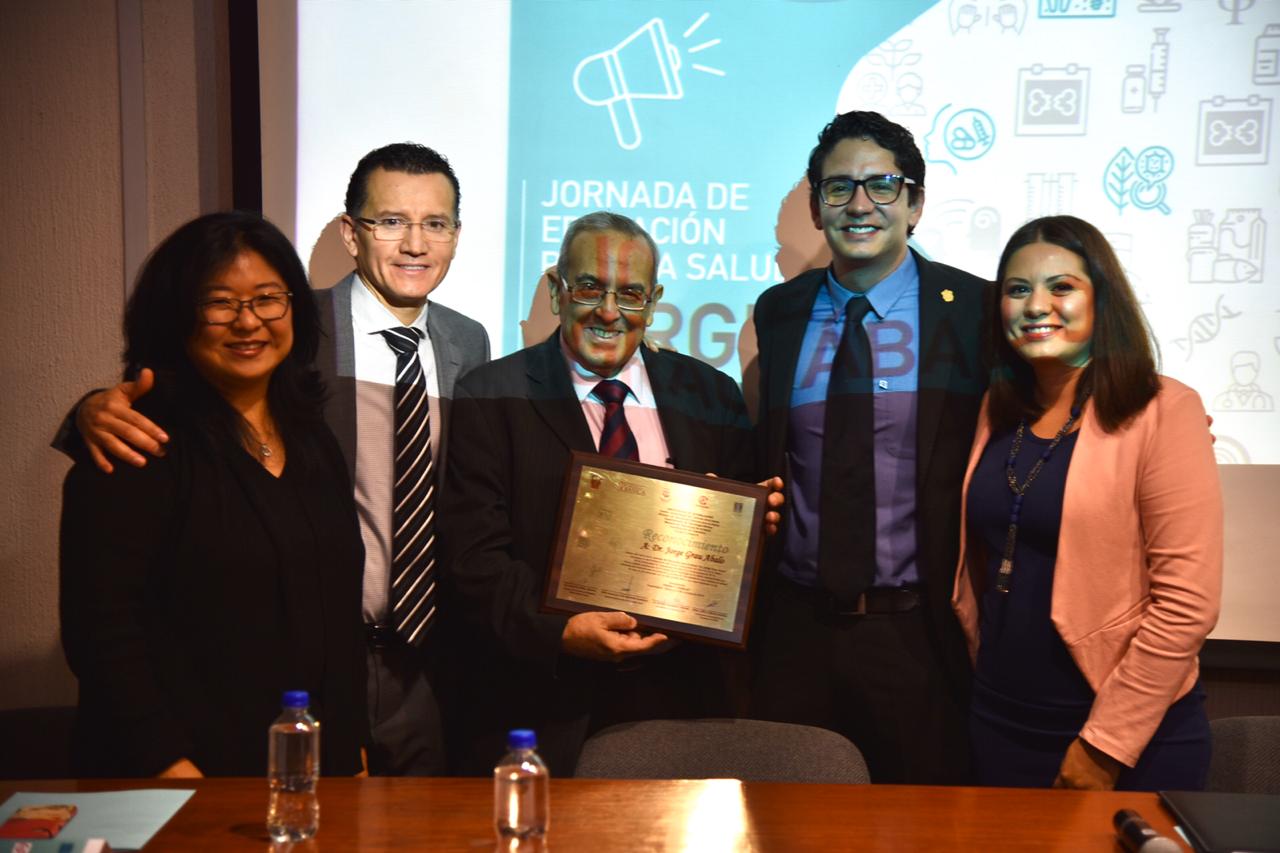 Foto grupal de miembros del presídium, el coferencista exhibe su reconocimiento