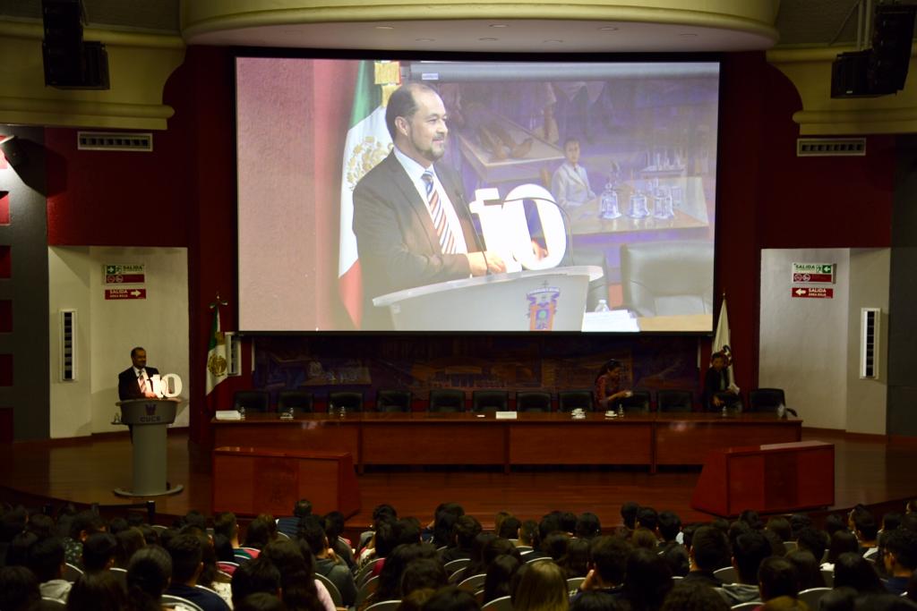 Toma general del auditorio desde la parte trasera. Al frente el ponente de la conferencia en la pantalla