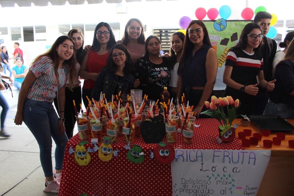 Alumnos atendiendo stand de verduras y frutas