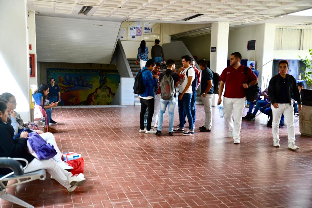 Alumnos del CUCS desplazándose con prisa por los pasillos del centro universitario
