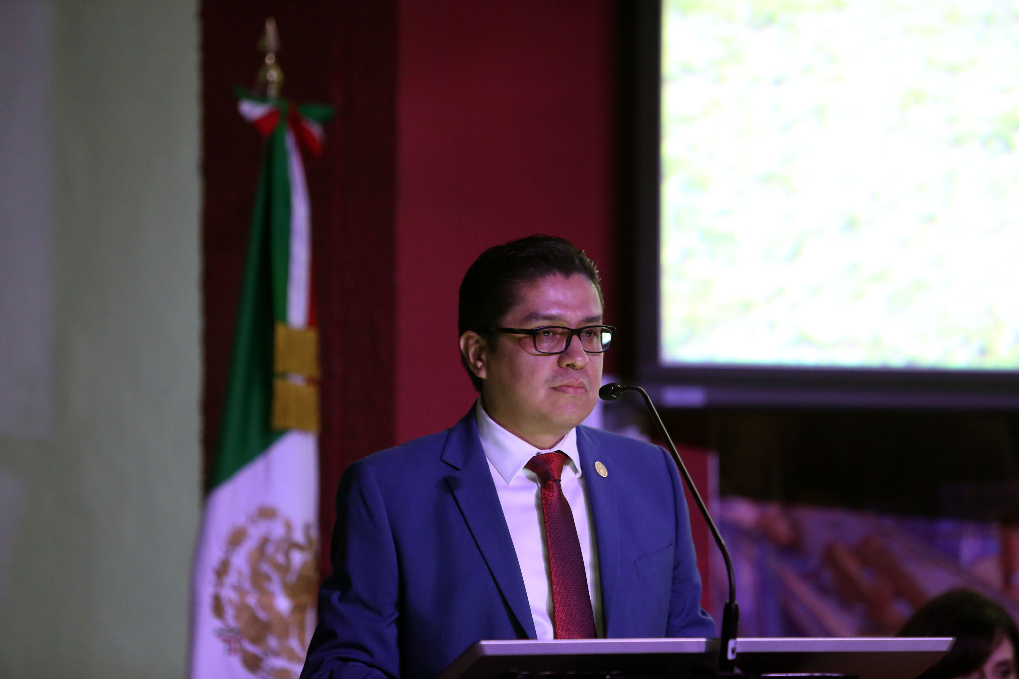 Rector CUCS al micrófono en pódium en informe de actividades