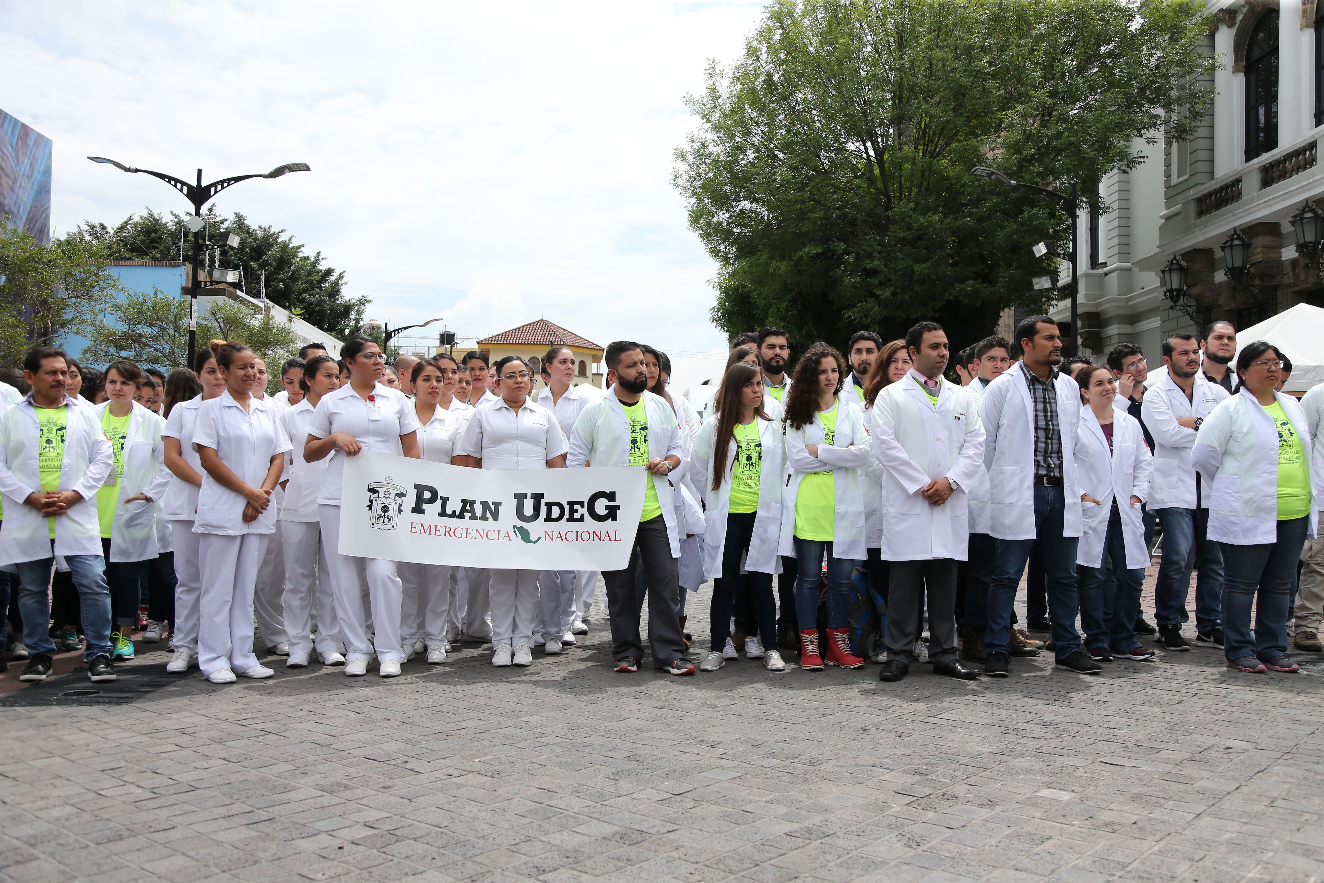 Brigadistas del CUCS con bata blanca posan para la foto y portan letrero "Plan UdeG Estrategia Nacional" en la Rambla Cataluña