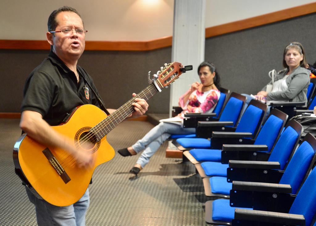Cantante tocando la guitarra y cantando frente al grupo en el auditorio