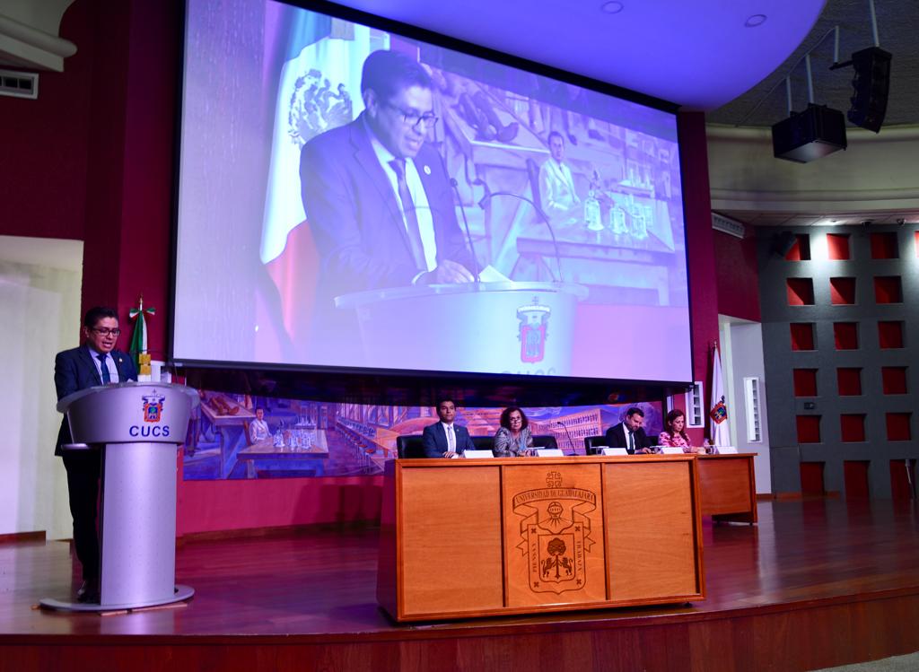 Vista general del presídium. Rector en pódium y pantalla gigante con su imagen