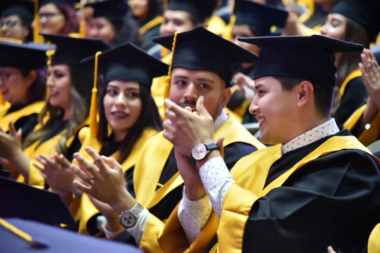 Foto cerrada de graduados luciendo toga y birrete aplaudiendo