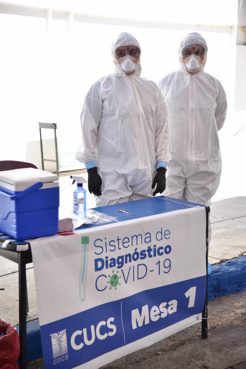 Personal con equipo de protección en mesa de toma de muestras del Drive Thru