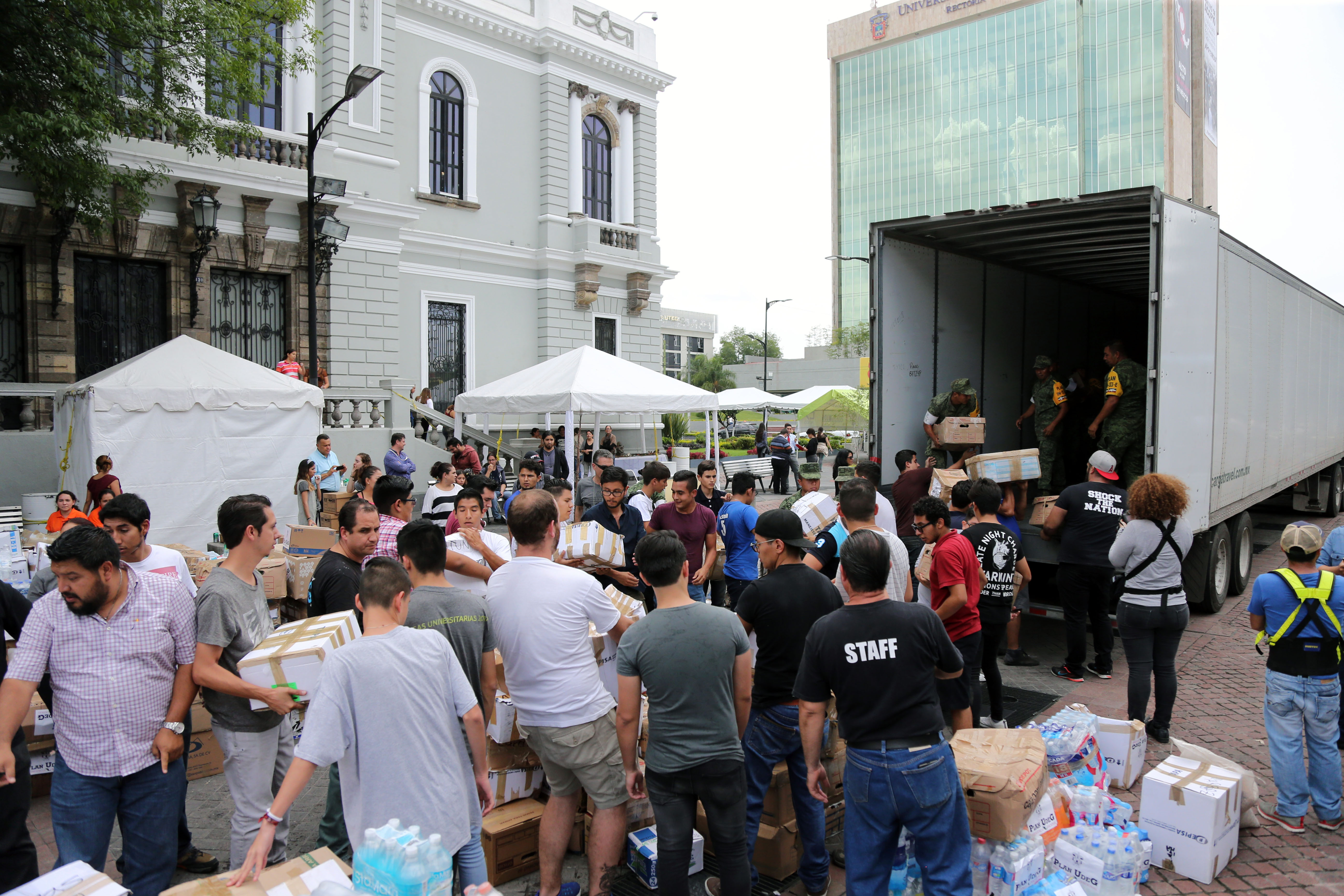 Decenas de voluntarios cargan productos acopiados al tráiler rumbo a Jojutla, Morelos.
