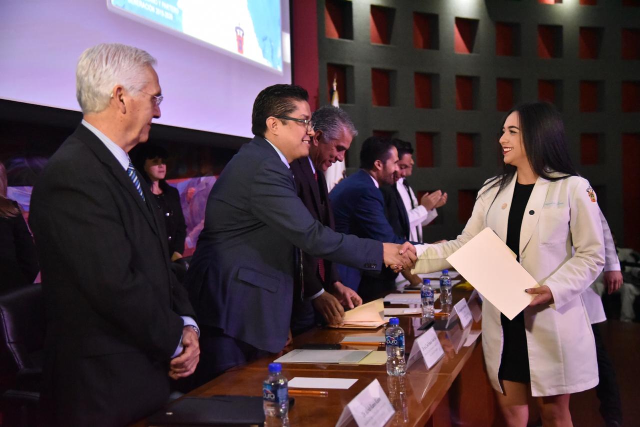 Alumna recibiendo de manos del rector su constancia