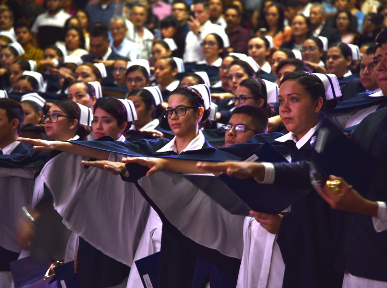 Graduadas rindiendo protesta de pie con el brazo extendido hacia el frente