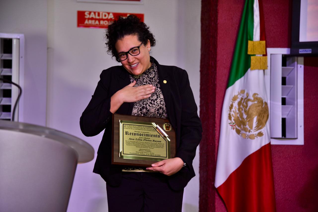 Madrina de generación exhibiendo reconocimiento y agradicendo con la mano