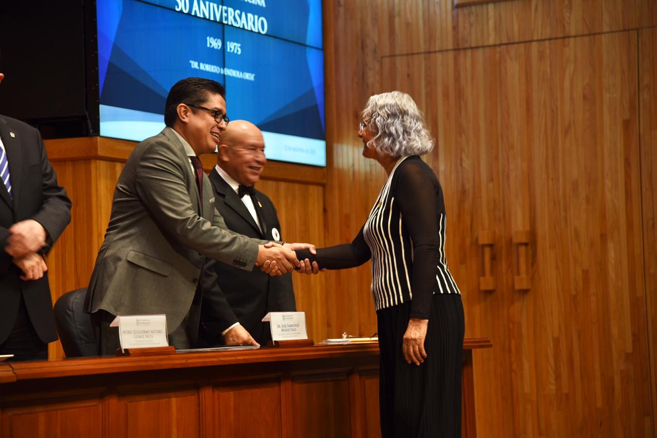 Dr. Muñoz entregando reconocimiento a egresada de la generación