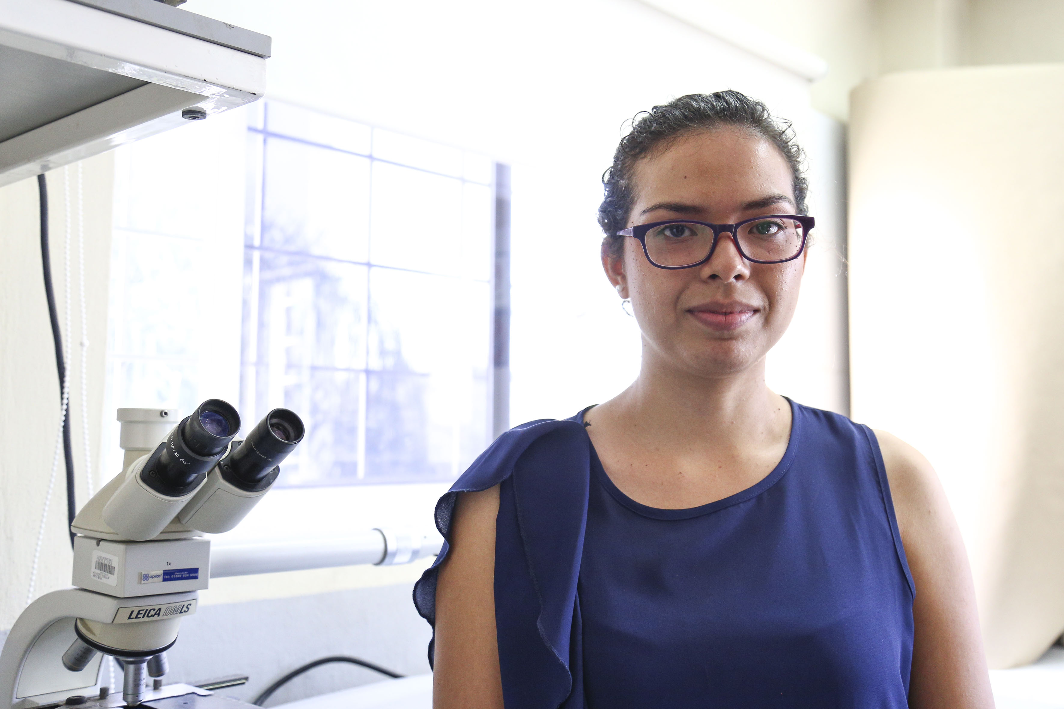 Estudiante de doctorado al lado del microscopio