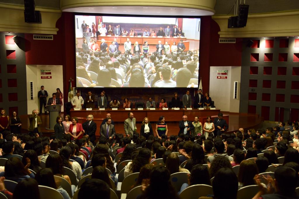 Toma general del auditorio, al frente los jefes y coordinadores de carrera saludando a los nuevos alumnos