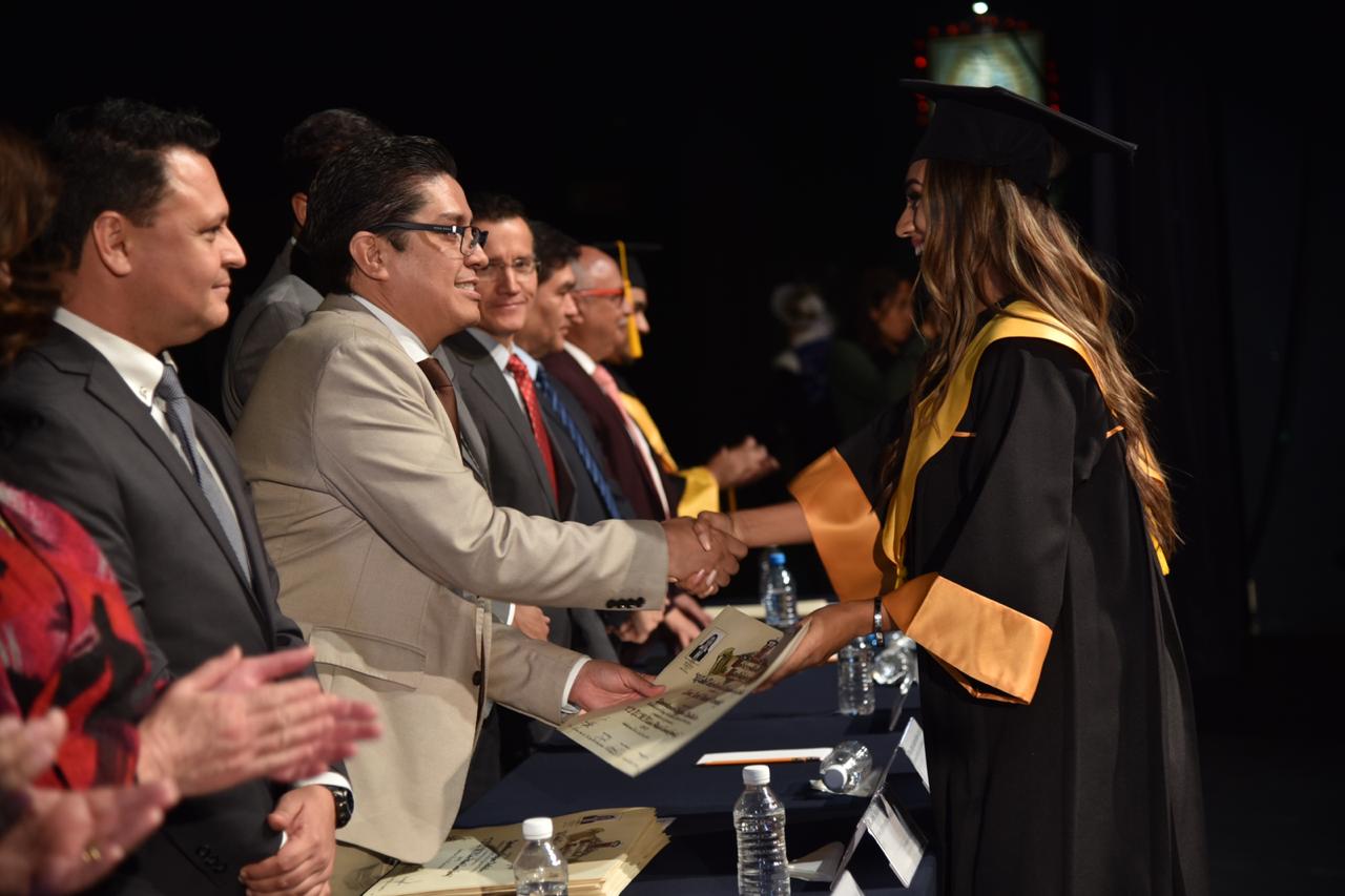 Rector entregando reconocimiento a graduada