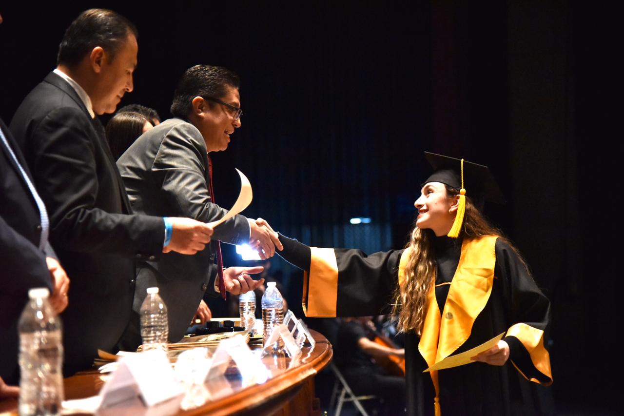 Rector del CUCS saludando a alumna graduada al entregarle su pergamino