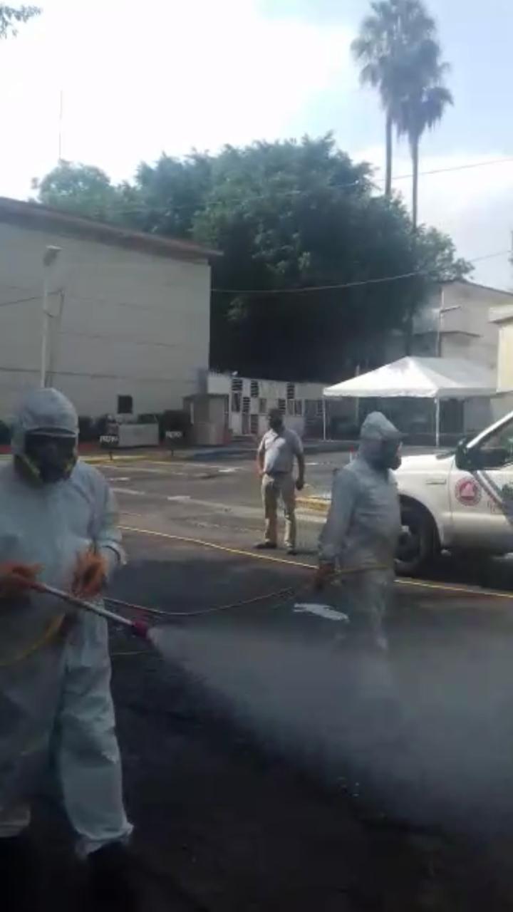 Personal de Protección Civil sanitiazando el estacionamiento de la puerta 13 del CUCS