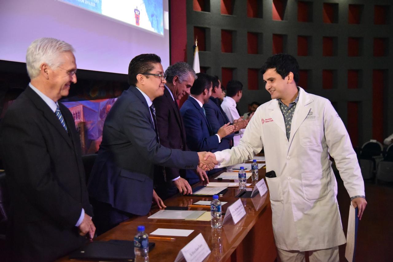 Alumno recibiendo de manos del rector su constancia