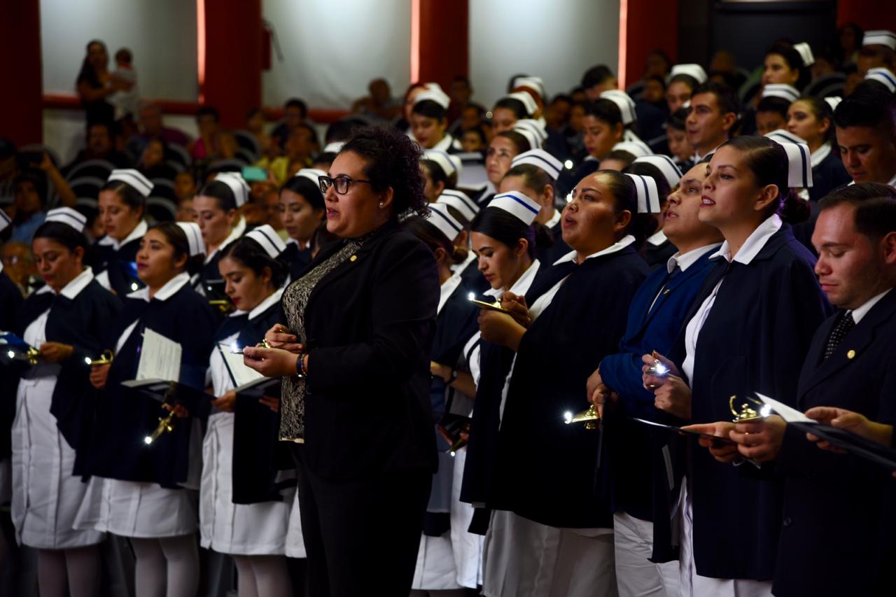 Graduados y madrina en la Ceremonia de la Luz con sus lámparas encendidas