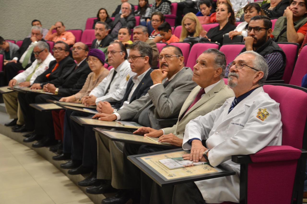 Médicos homenajeados escuchando discursos con su reconocimiento