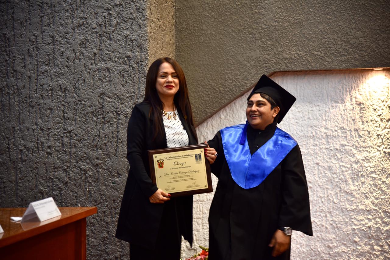 Madrina de generación y representante de los graduados posan para la foto 