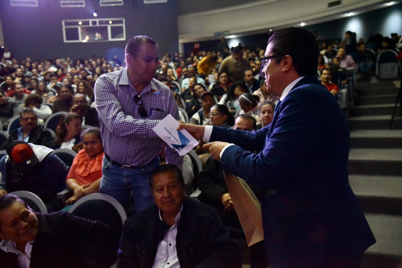 rector del cucs entregando paquete de libros a padres de familia en su butaca