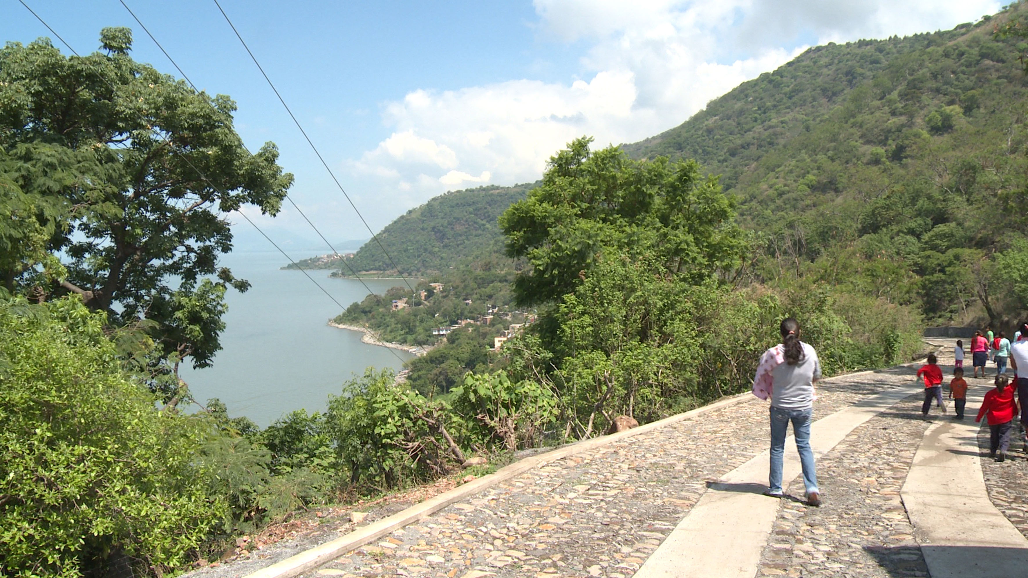 camino de Agua Caliente, niños transitando a pie y una señora cargando a su bebé