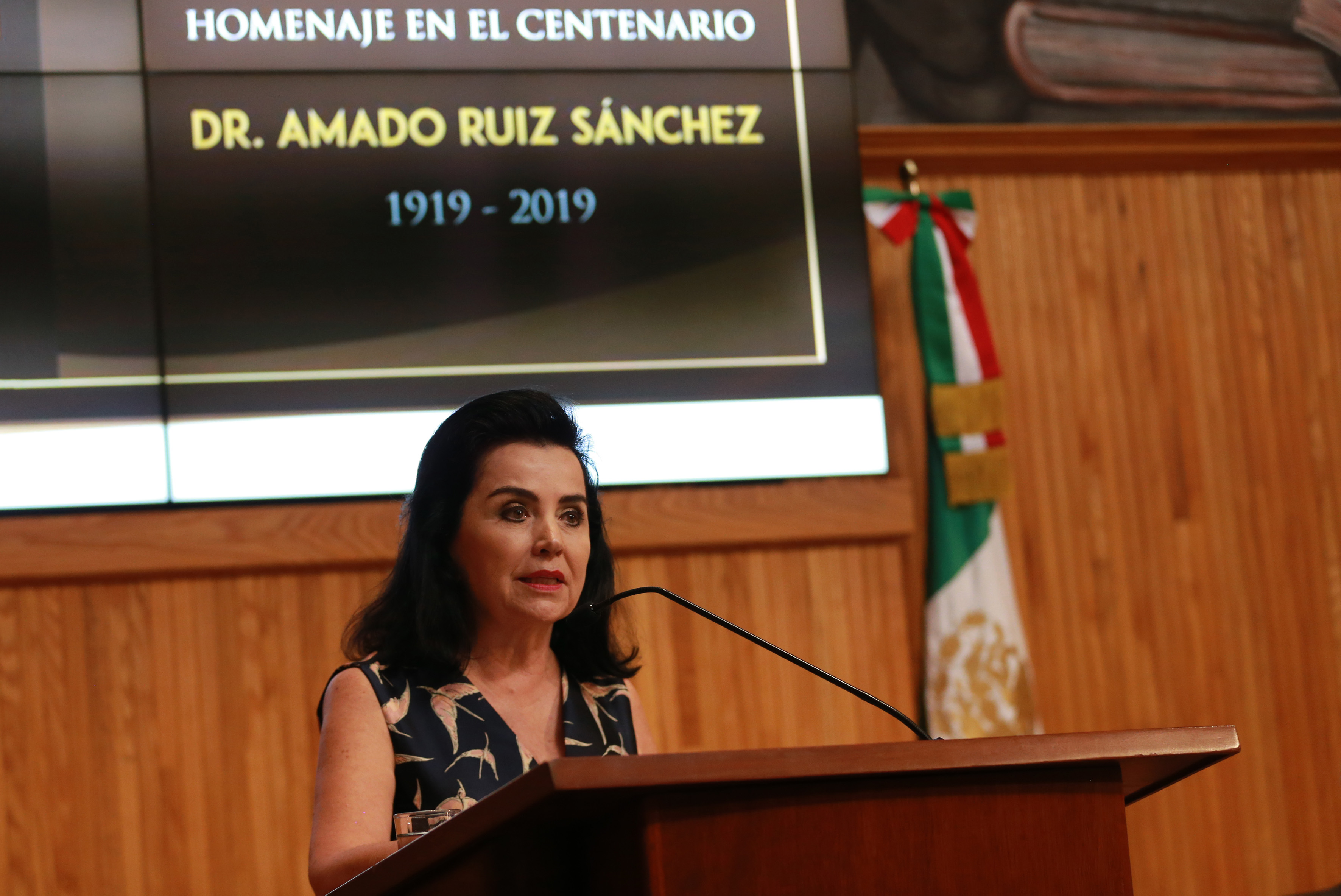 Hija del homenajeado al micrófono en pódium