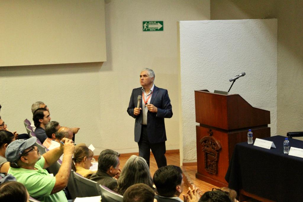 Funcionario de la SSJ impartiendo conferencia, toma desde arriba del auditorio