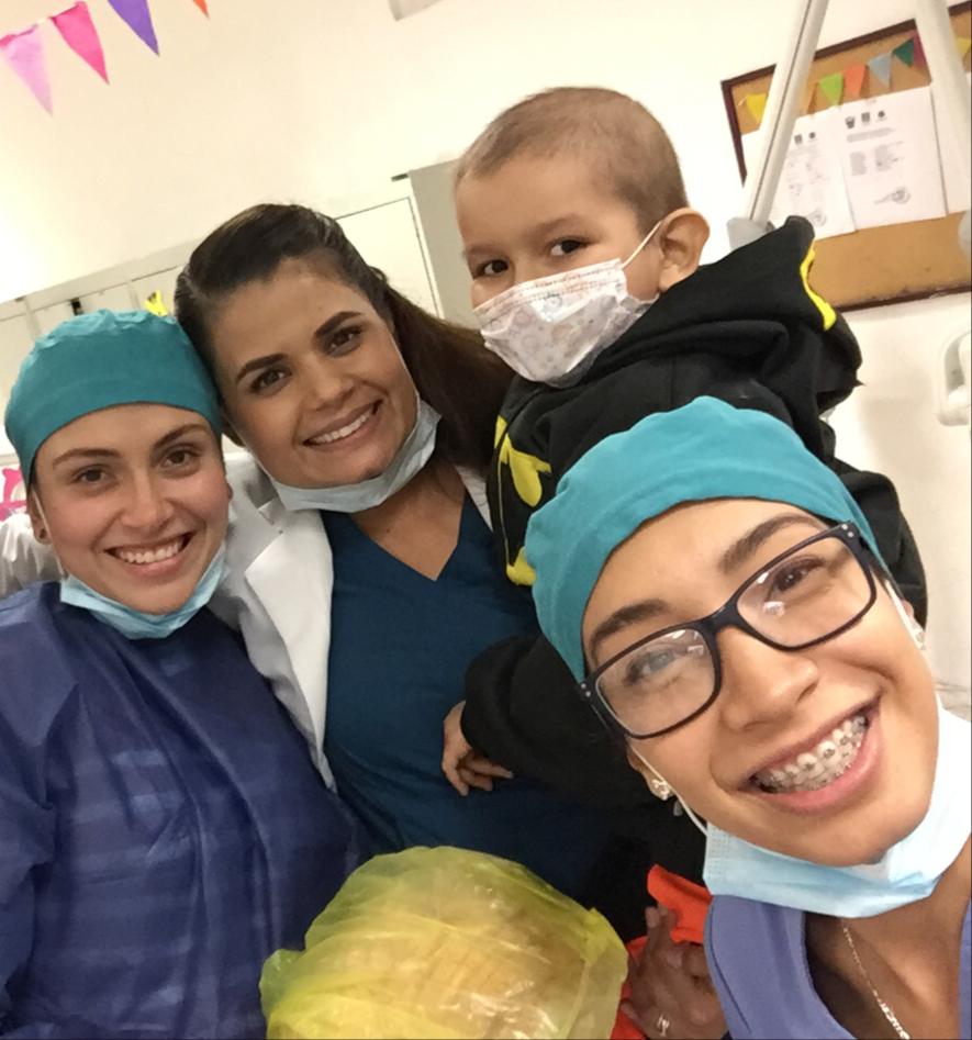 Grupo de odontopediatras cargando en brazos a un pacientito