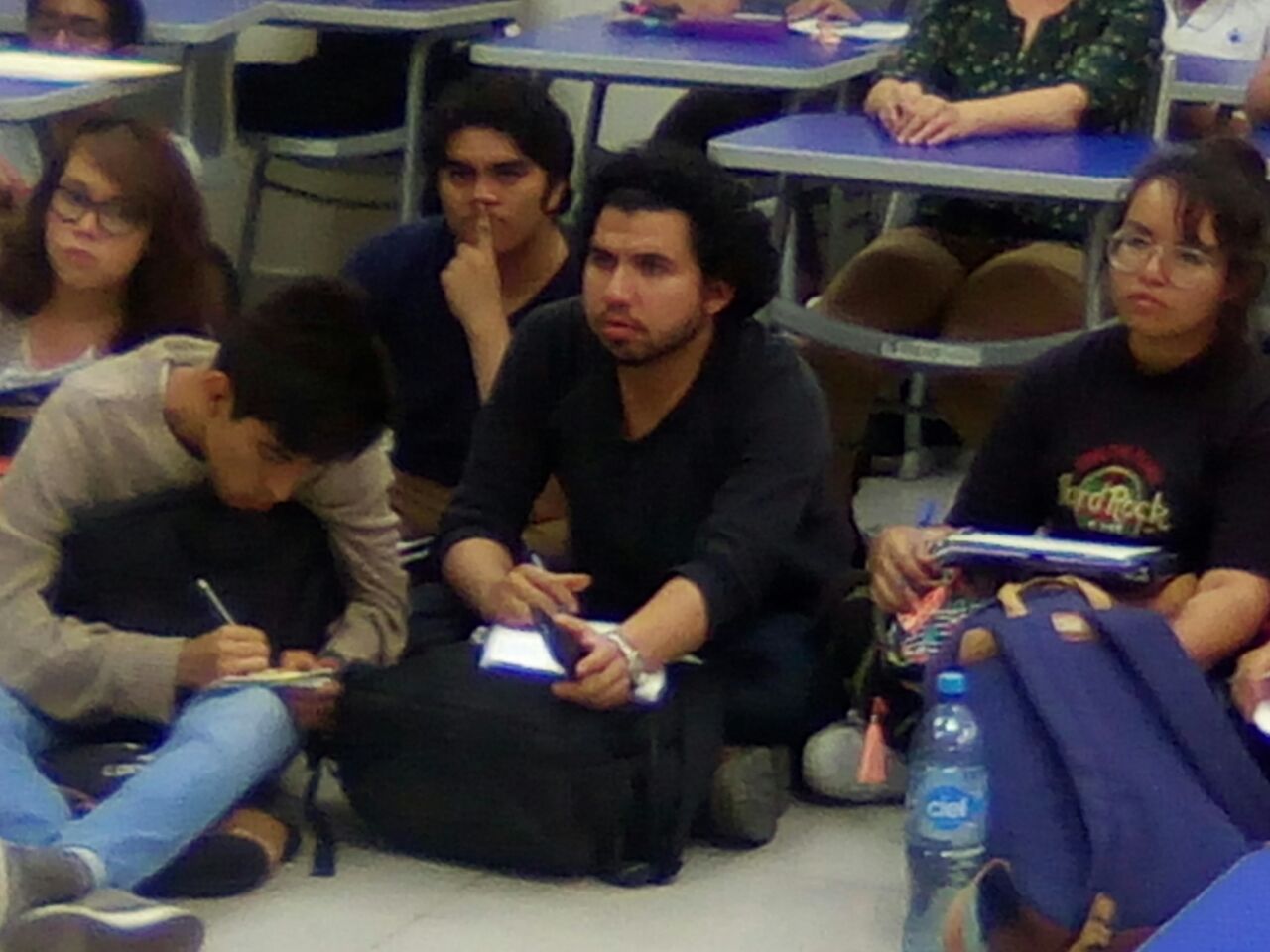 Alumnos sentados en el suelo durante el conversatorio